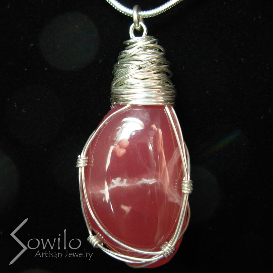 A silver pendant with a pink stone